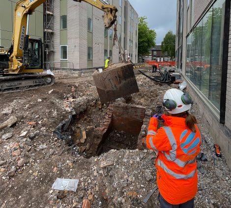 Engineer photographing the removal of an underground tank during brownfield excavation works