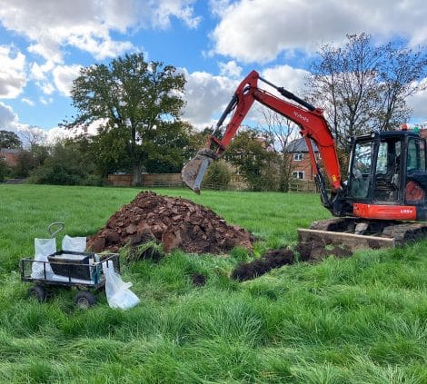 Greenfield trial pitting with a mini excavator digging soil to support materials management and site investigation work.