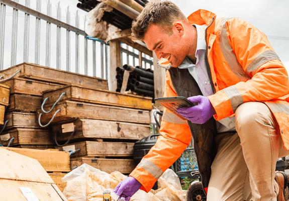 Environmental consultant collecting soil samples on site using tablet for recording data